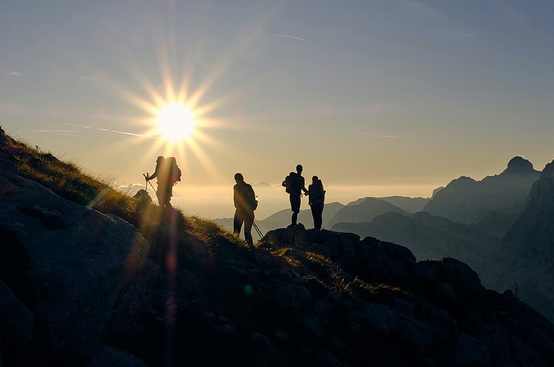 Gruppe Menschen beim Wandern auf Bergkamm mit Blick auf Sonnenuntergang