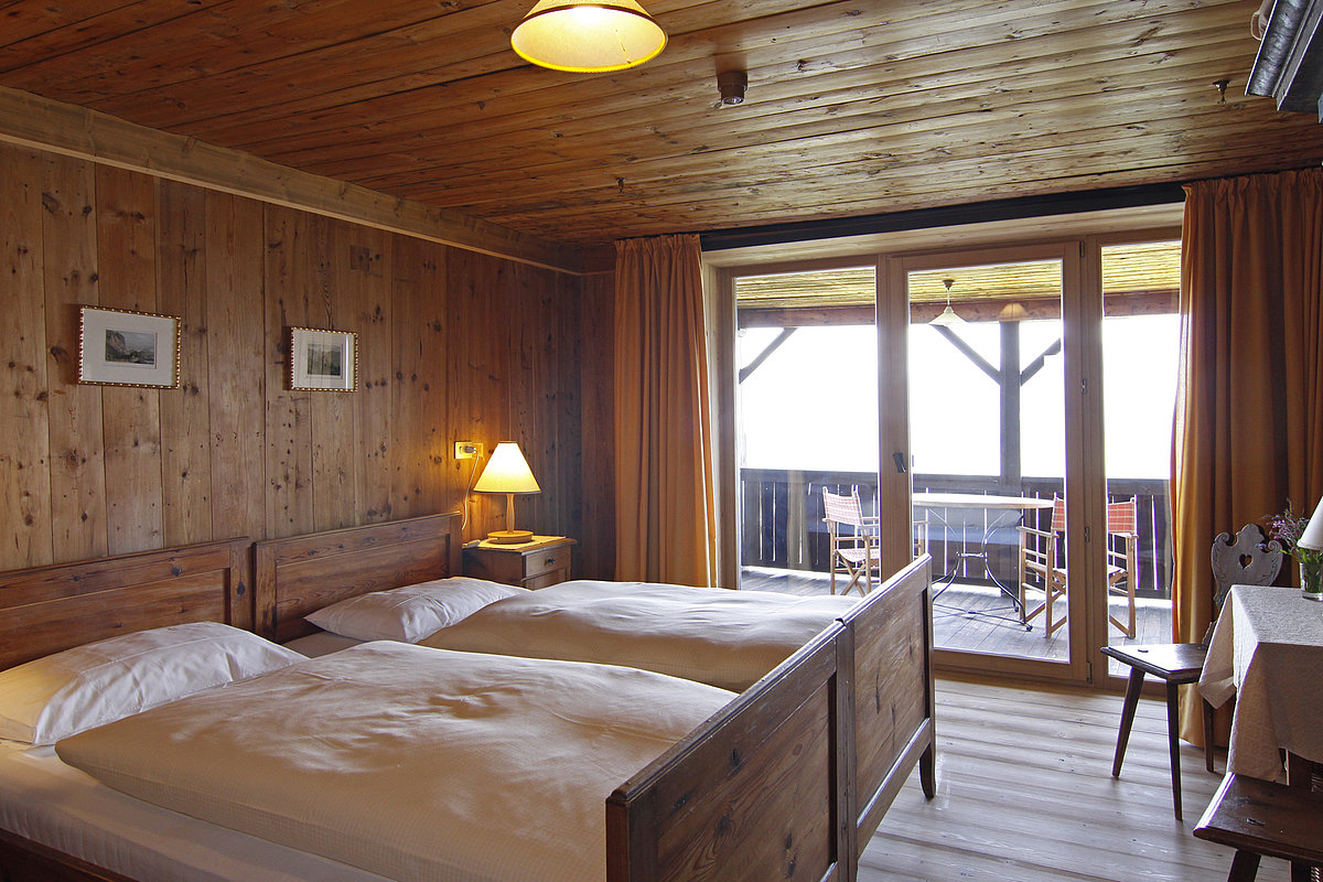 Hotelzimmer aus Holz mit Doppelbett und Balkon