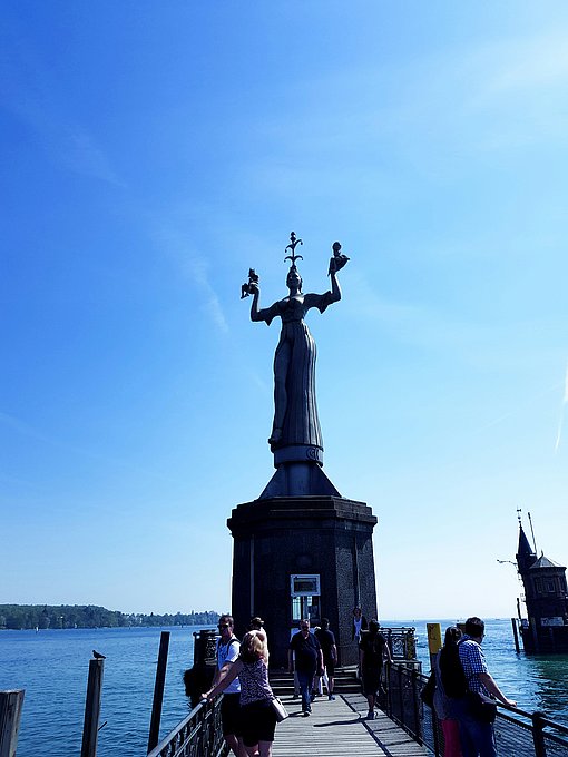 Eine Stahlstatue, die zwei zwerghafte nackte Männlein in ihren erhobenen Armen hält