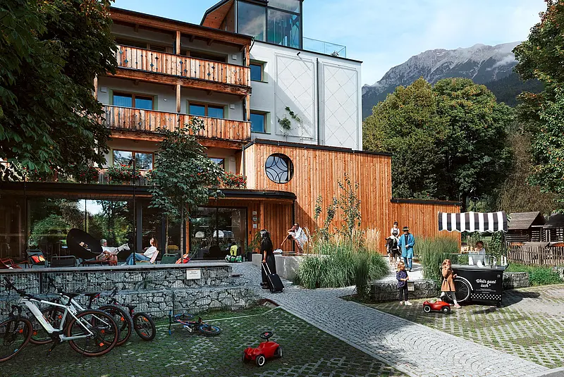 Ansicht einer Hotelfassade mit einem mit Menschen belebten Vorplatz 