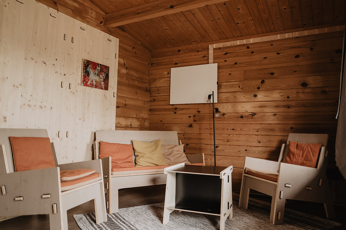 Innenansicht Holzhütte mit Sesseln, Teppich und Couchtisch