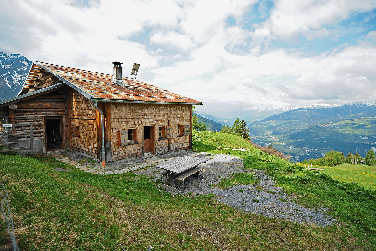 Eine Alphütte mit Ausblick auf einer grünen Wiese in der Schweiz
