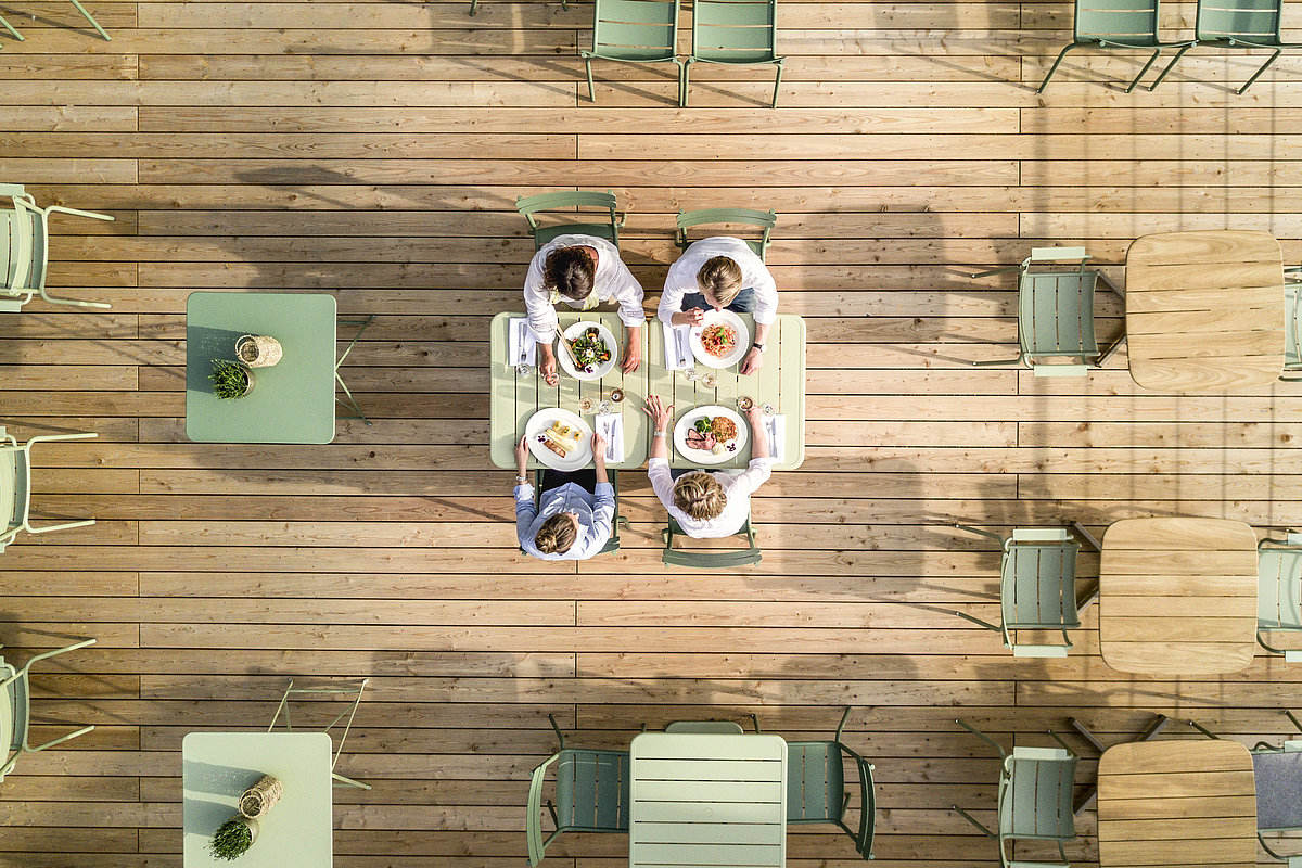 Vier Personen beim Essen auf einer Terrasse aus der Vogelperspektive
