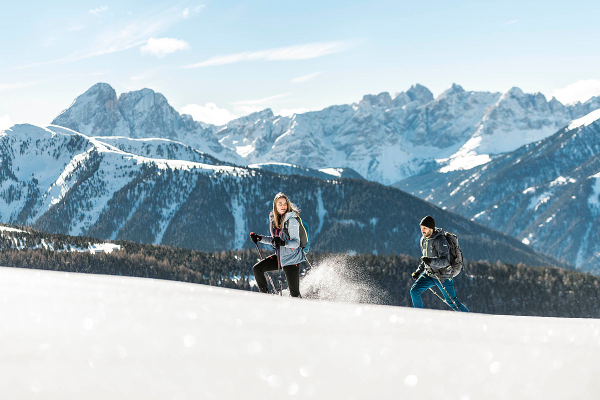 Zwei Personen wandern durch den Schnee, Alpenlandschaft