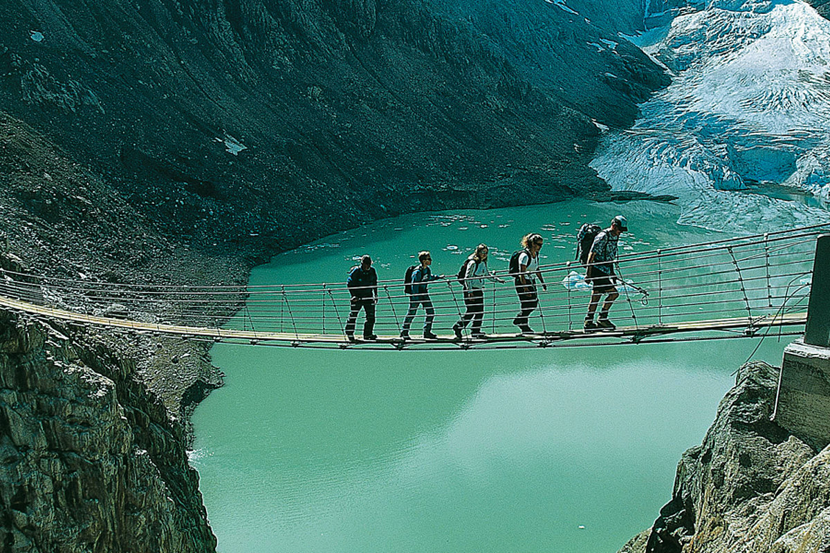 Mehrere Menschen laufen über eine Hängeseilbrücke im Berner Oberland zwischen zwei Bergen