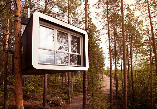 Ein modernes Baumhaus mit großer Fensterfront im Wald