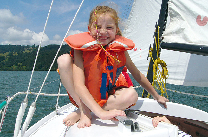 Ein lachendes Mädchen mit Schwimmweste auf einem Boot