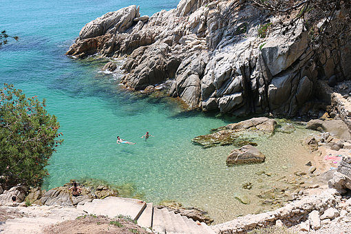 Ein junges Paar schwimmt in einer Bucht an der Costa Brava.
