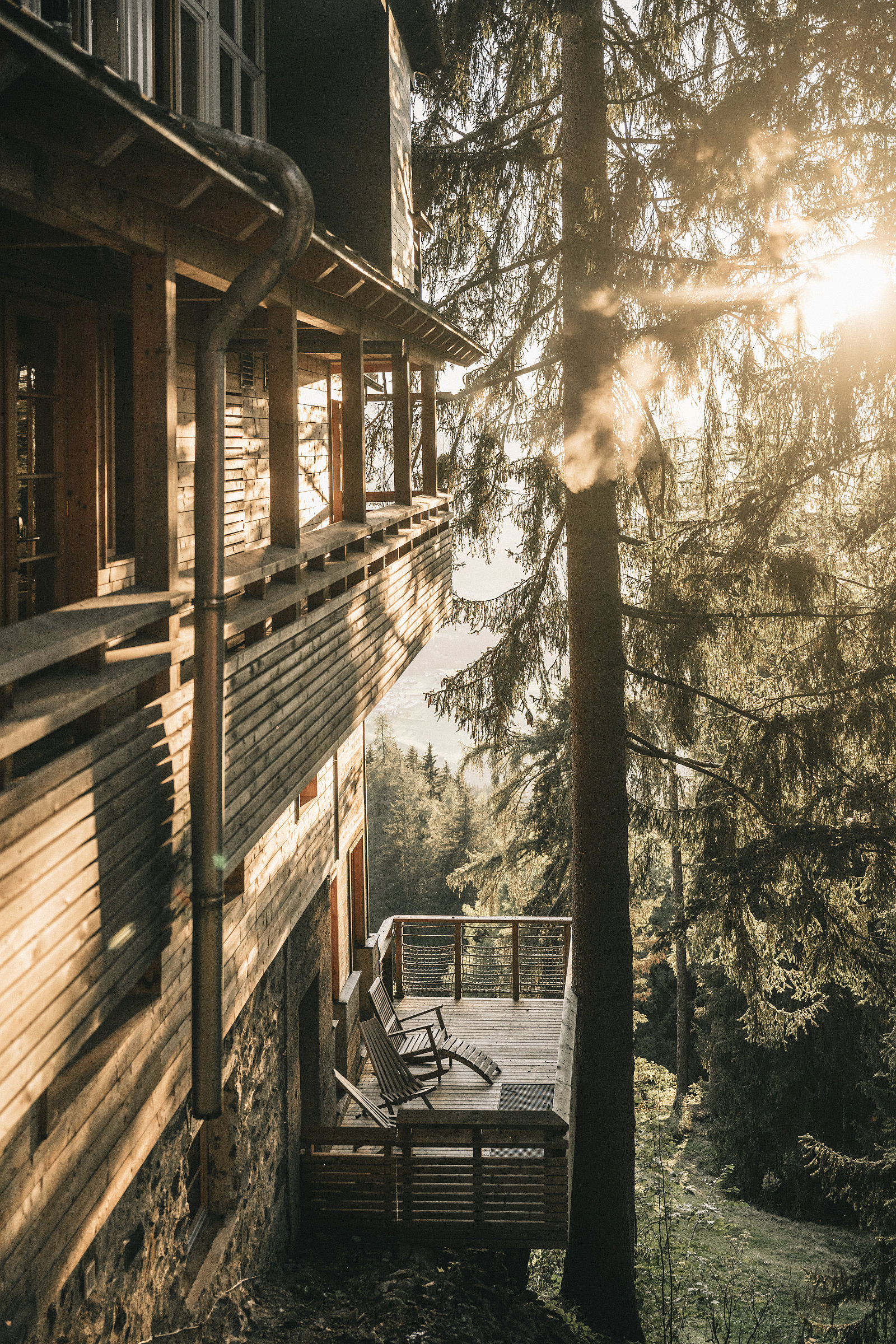 Außenansicht eins Hotel, das vollständig mit Holz umkleidet ist. Ein kleiner Balkon ist zum angrenzenden Wald ausgerichtet.