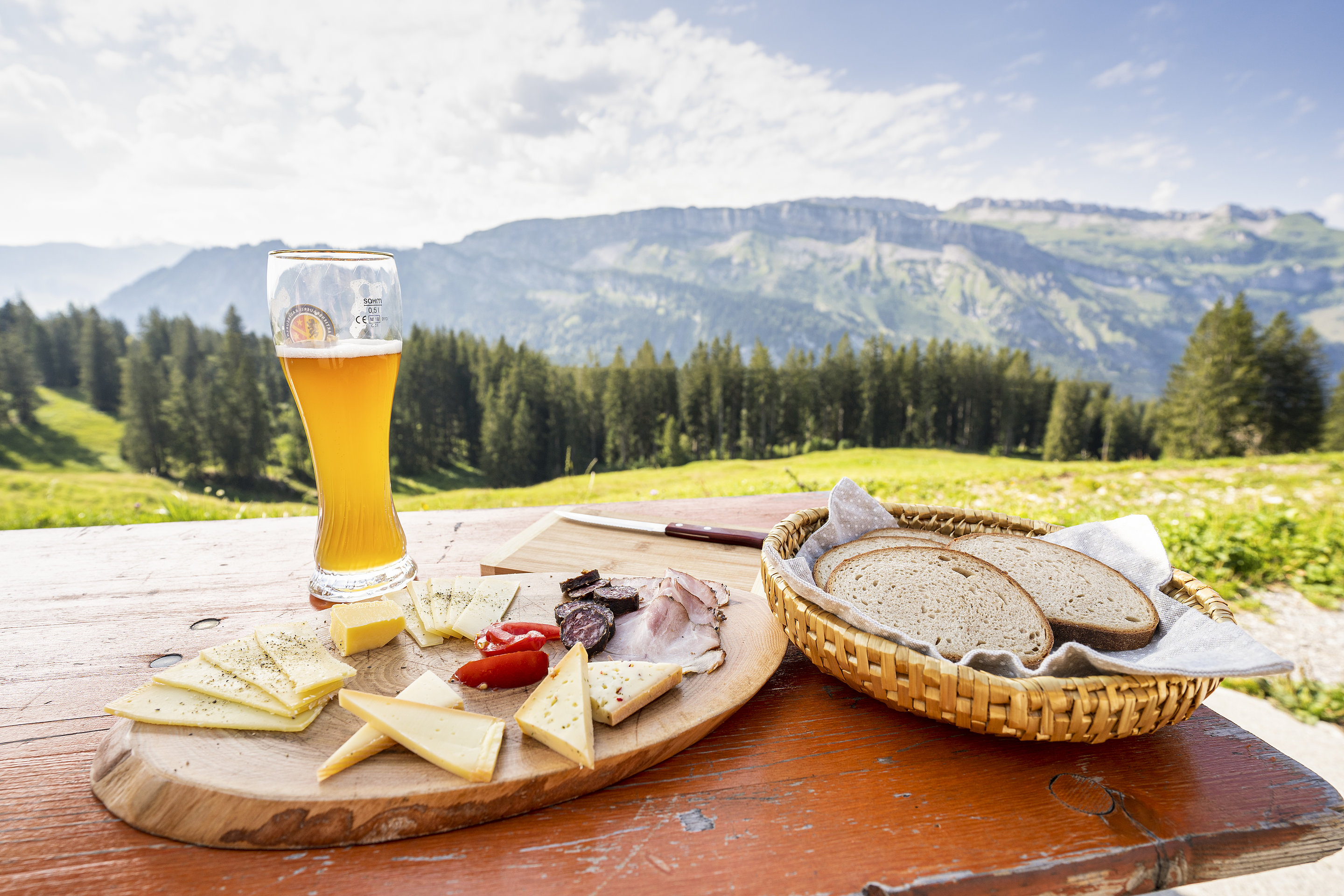Brotzeit mit Bierglas auf einem Biertisch mit Ausblick auf die Berg