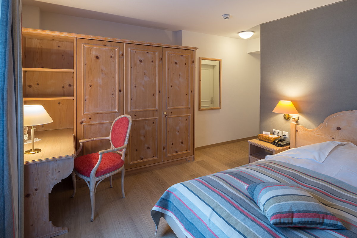 Ein Hotelzimmer mit Holzschrank, Bett und Schreibtisch