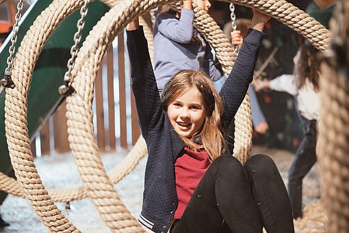 Ein Mädchen klettert durch einen Seilring