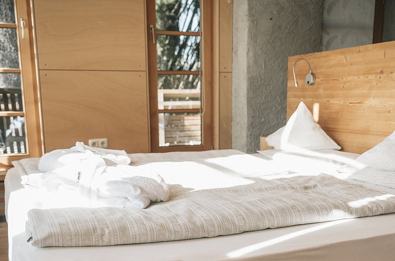 Hotelzimmer mit gemütlichem Bett und viel unbehandeltem Holz