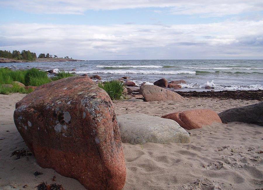 Sandstrand mit großen Steinen vor ruhigem Meer