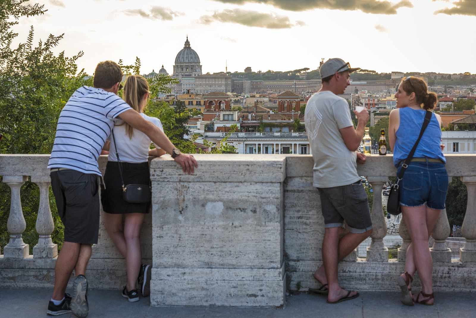 Vier Personen stehen an einer Balustrade mit Blick auf Rom