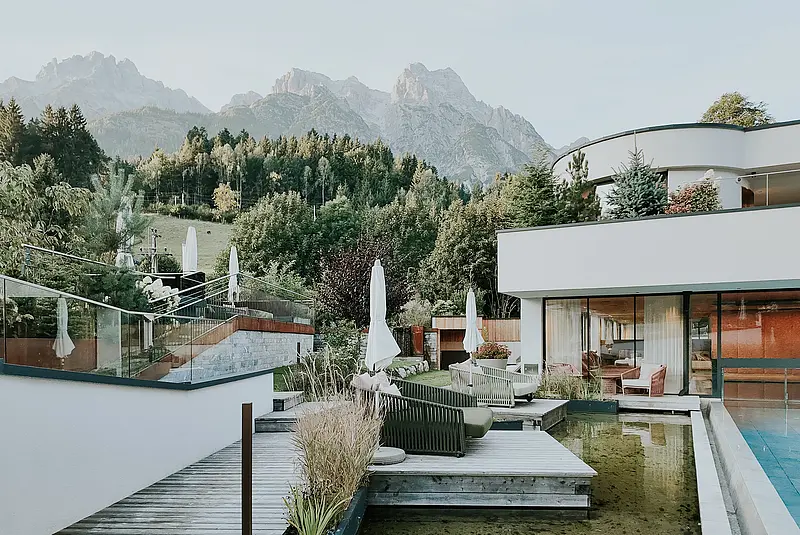Außenansicht des weißen Hotels mit Außenpool vor Bergpanorama
