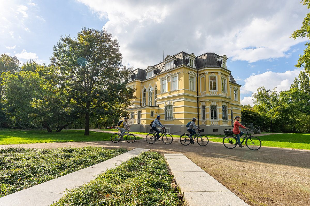 Vier Radfahrer radeln durch einen Schlosspark