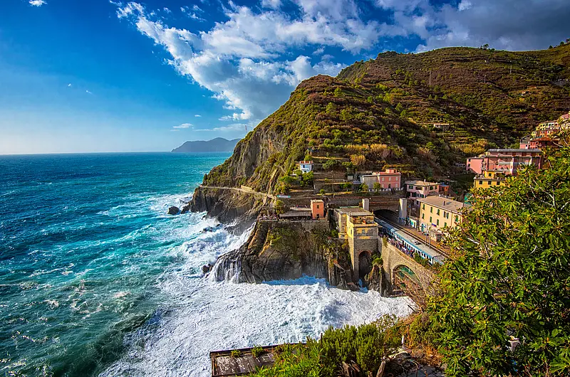 Ein Zug fährt an einer italienischen Küste vorbei mit Meerblick.