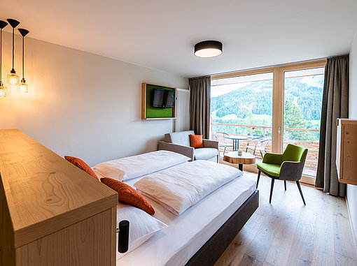 Ansicht Hoteldoppelzimmer mit Balkon und Blick auf bewaldete Berge