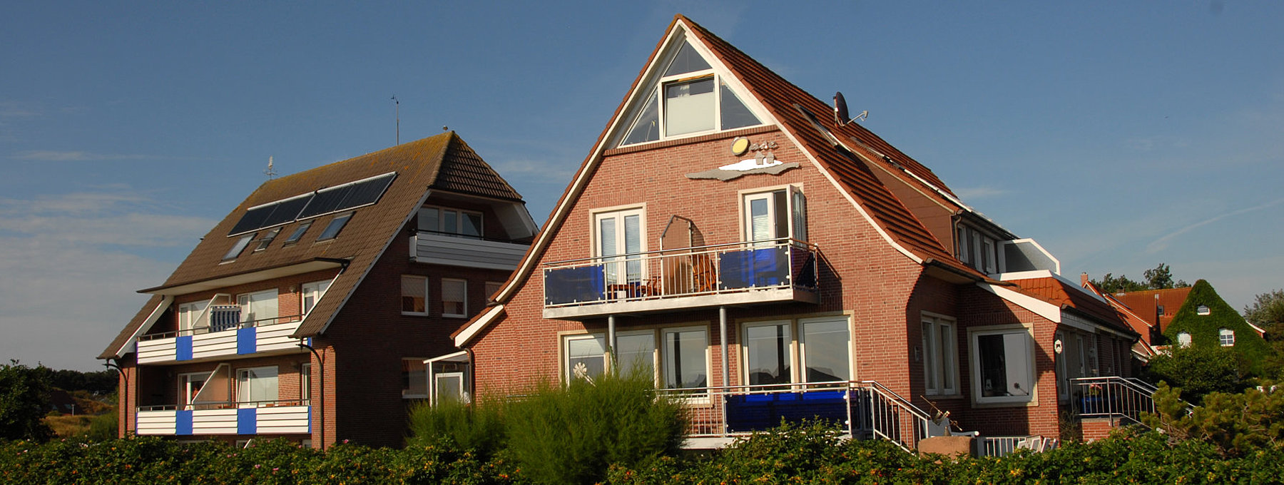 Backstein-Ferienhäuser mit Balkonen und grüner Hecke