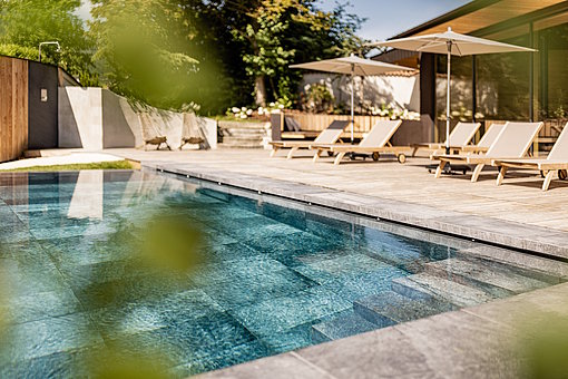 Pool mit Liegen und Sonnenschirmen am Rand