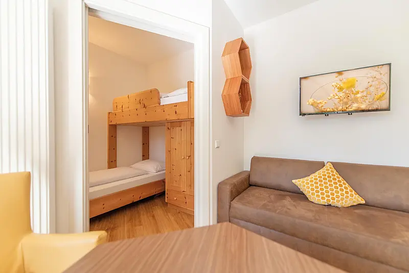 Wohnzimmer eines Apartments mit Blick in ein benachbartes Schlafzimmer mit Stockbett