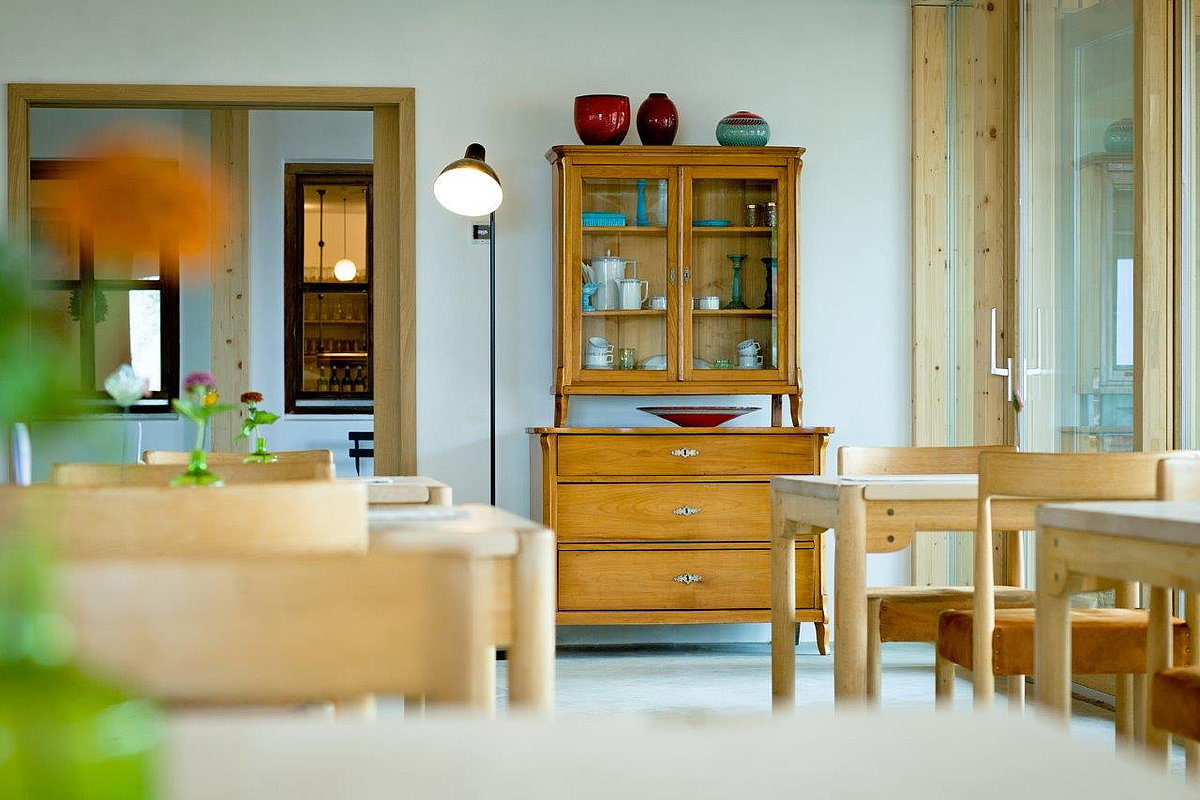 Raum mit Holzvitrine, Holztischen und Holzstühlen