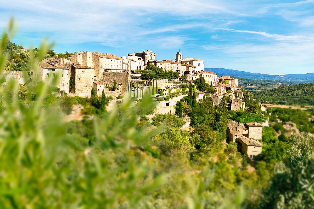 Ein Dorf in der Provence inmitten von grünen Bäumen und Sträuchern bei blauem Himmel