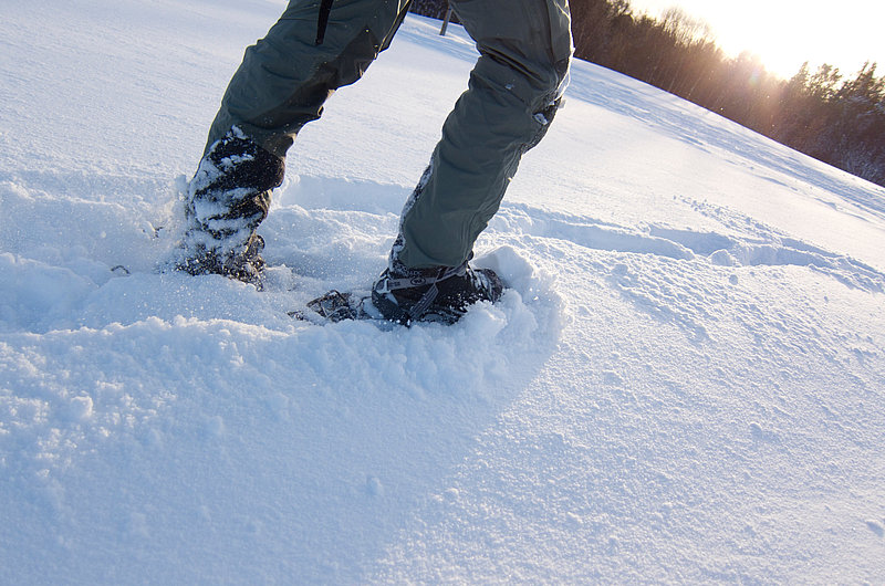 Beine mit Schneeschuhen stapfen durch hohen Schnee
