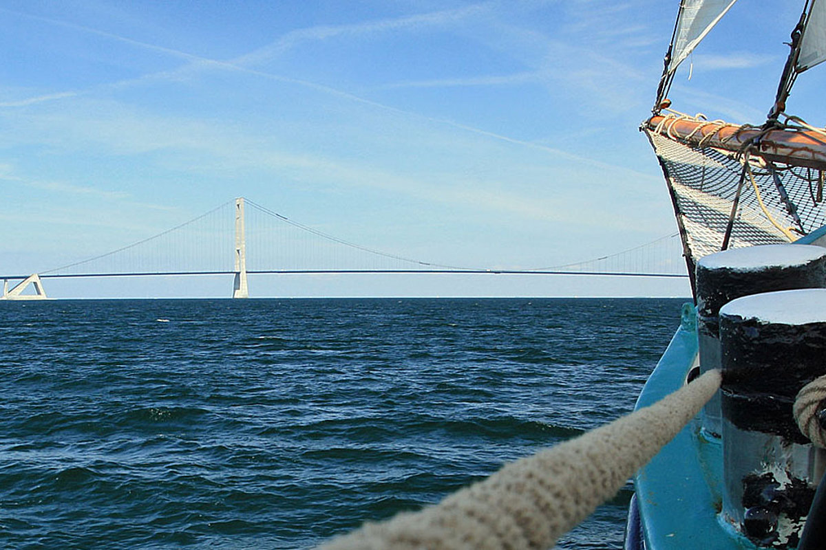 Schiffspitze mit Mast fährt auf eine Brücke zu