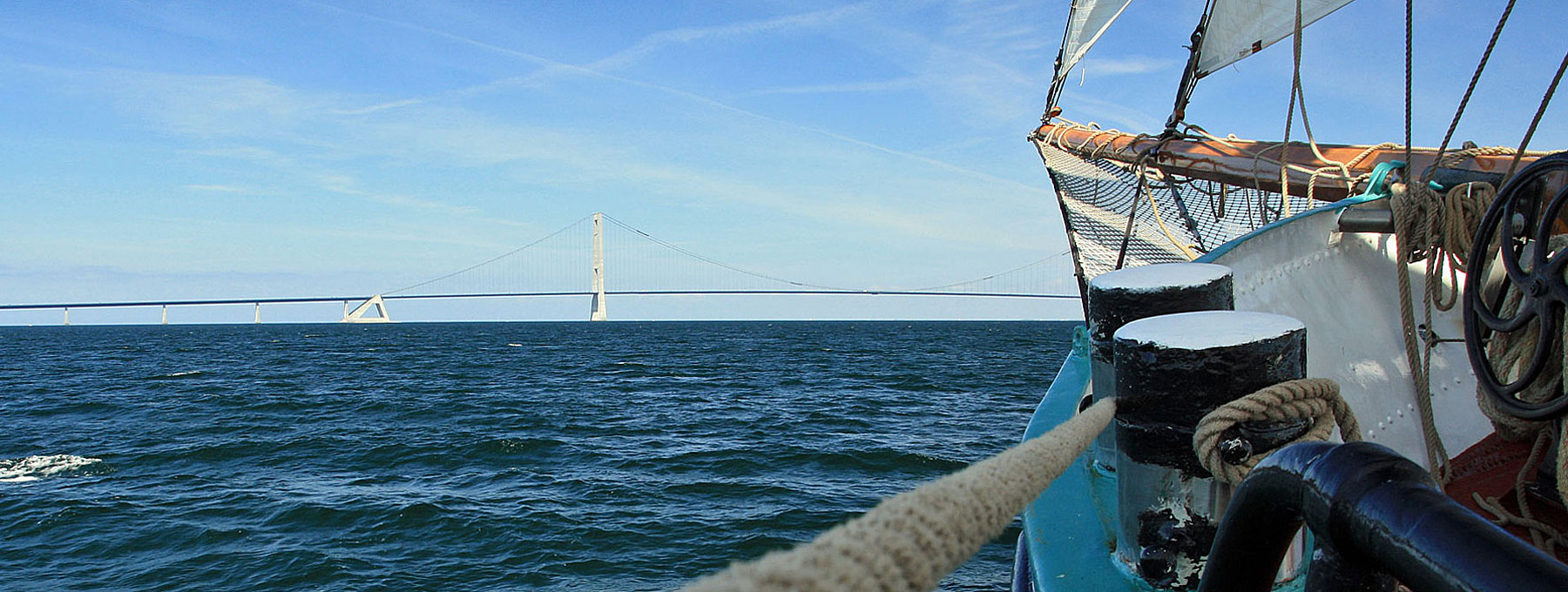 Schiffspitze mit Mast fährt auf eine Brücke zu