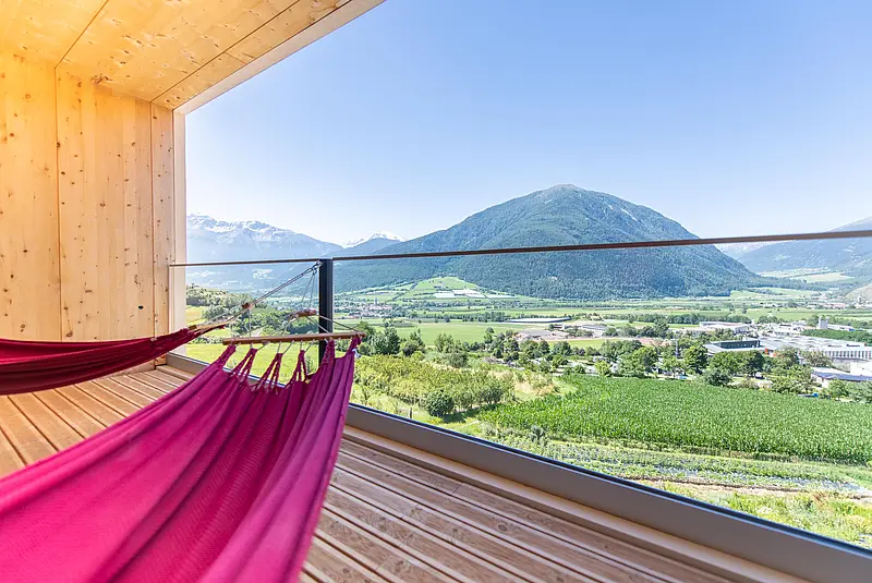 Teilansicht eines Hotelzimmerbalkons mit Hängematte und Blick in die Landschaft