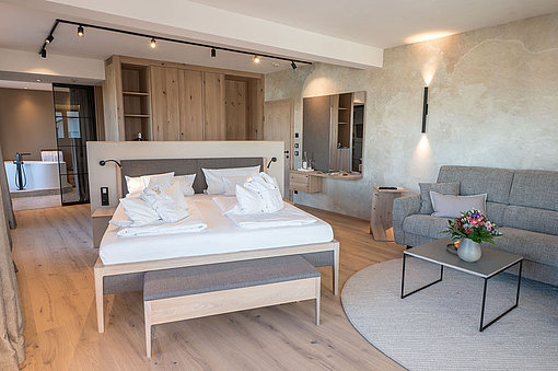 Blick in ein geräumiges Hoteldoppelzimmer mit Doppelbett und Sofa